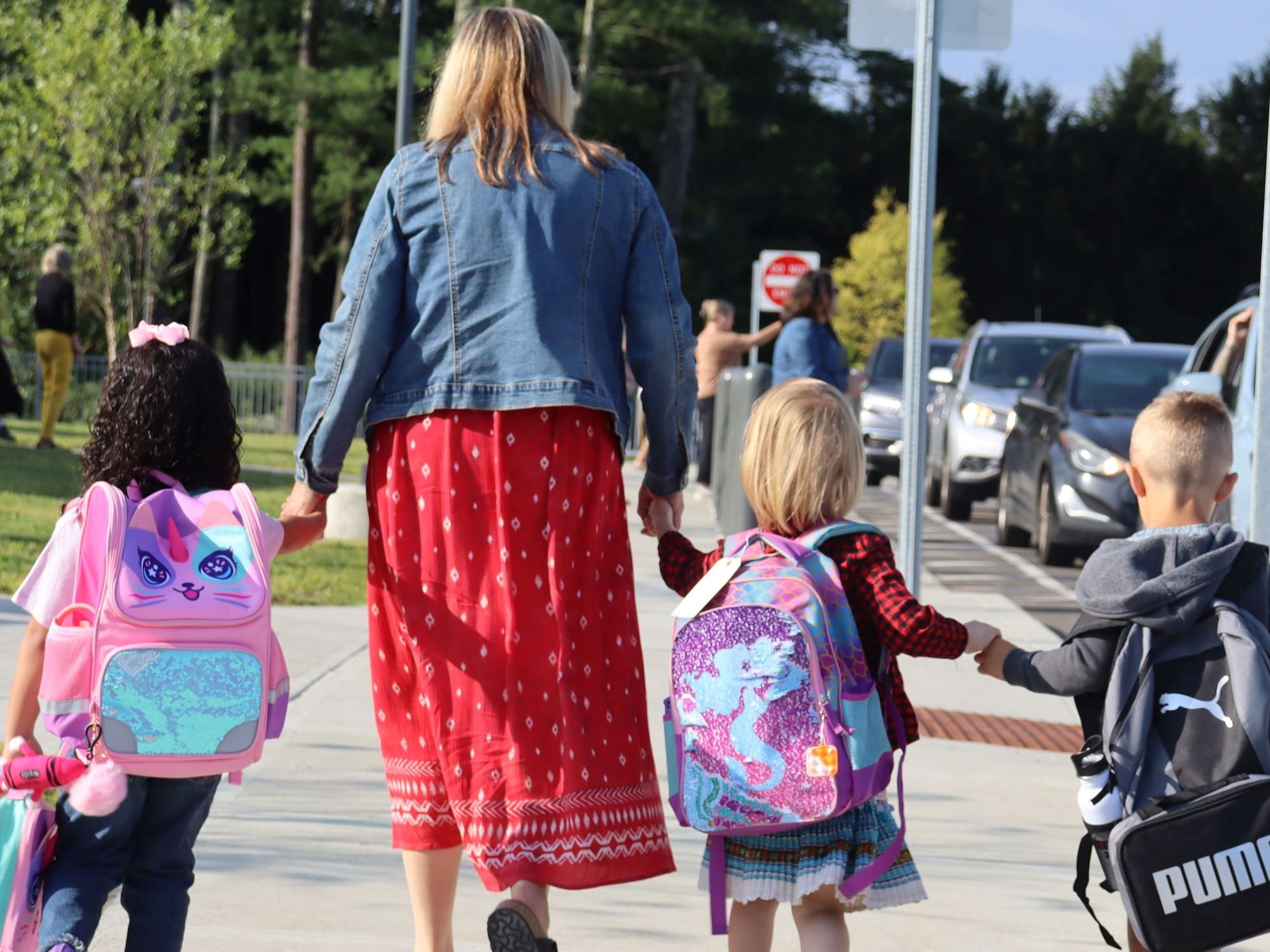 Teacher leading preschoolers into school