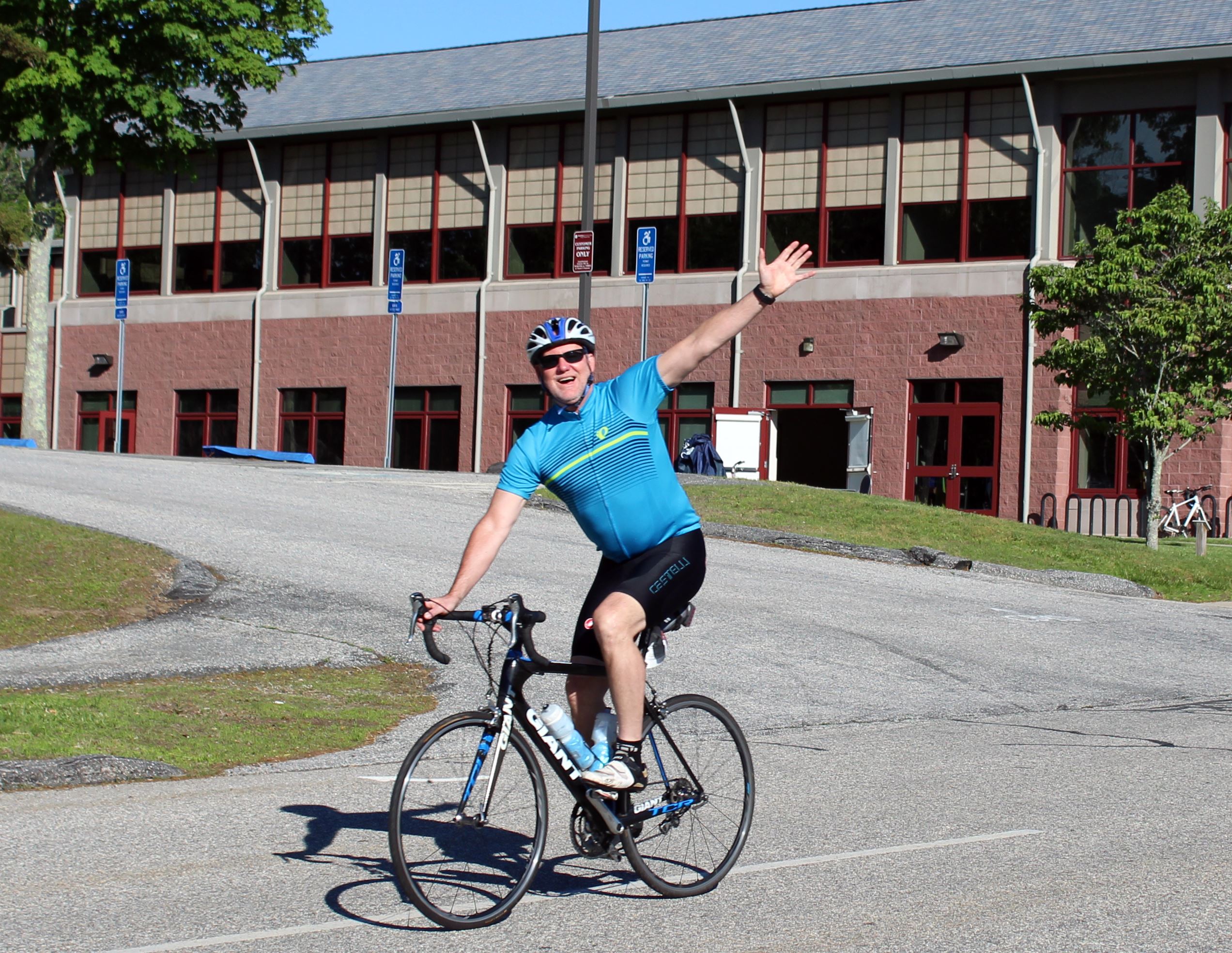 Man smiling and waving from his bicycle