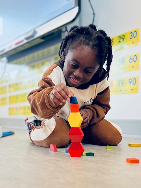 Kindergarten child stacks blocks